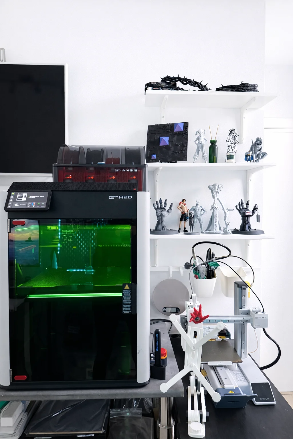 Bambu Lab H2D and A1 Mini 3D printers with finished prints